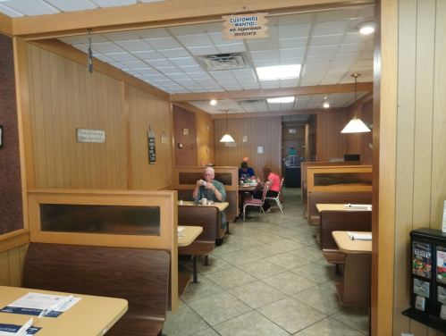 A cozy diner interior with wooden booths, a few patrons, and a welcoming atmosphere.