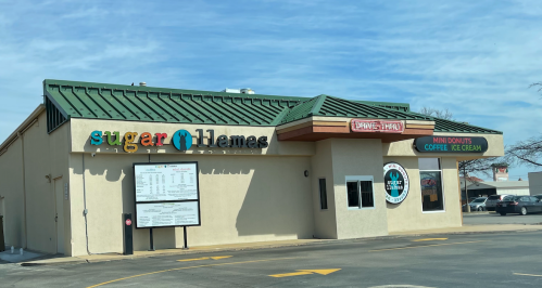 Exterior of a building with signs for "sugar" and "ice cream," featuring a drive-thru and menu board.