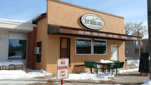 Exterior of Hay Creek Grill with a sign reading "Good Food - Good Friends - Good Times" and a "No Parking" sign nearby.