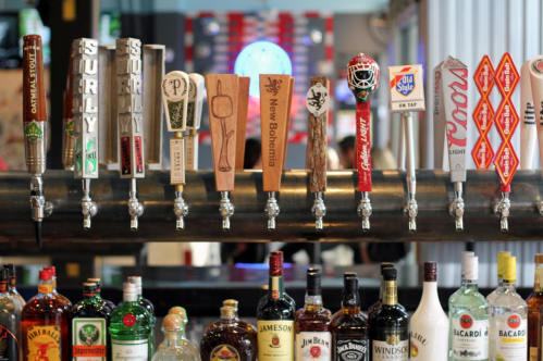 A variety of beer taps and liquor bottles displayed on a bar counter.