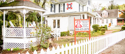 A charming Victorian bed and breakfast with a white picket fence and colorful quilt square on the facade.