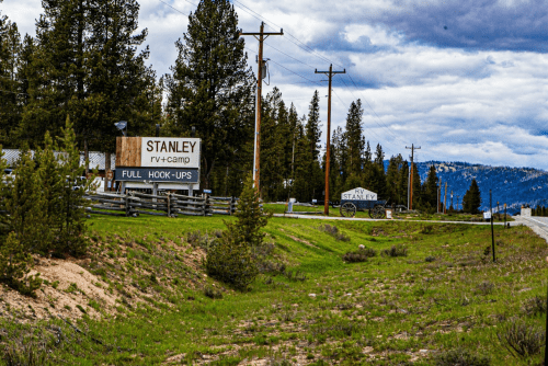 Sign for Stanley RV Camp with "Full Hook-Ups" displayed, surrounded by trees and a cloudy sky. Roadside view.