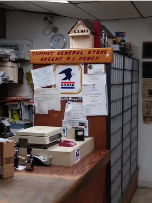 Interior of a general store with a post office, featuring mailboxes and a sign for Summit General Store, Greene, RI.