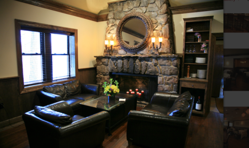 Cozy living room with a stone fireplace, leather chairs, a glass table, and a mirror above the mantel.