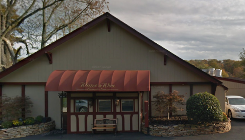 Exterior of a restaurant named "Water & Wine," featuring a red awning and landscaped entrance.