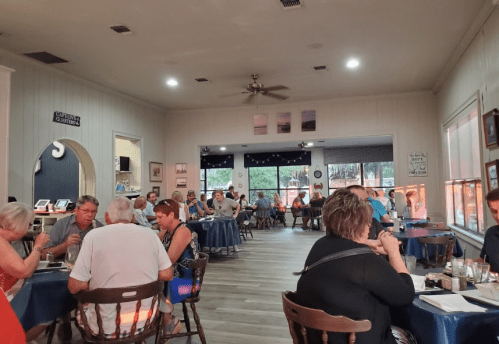A bustling restaurant interior with diners at tables, warm lighting, and decor on the walls.