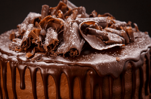A rich chocolate cake topped with chocolate shavings and a glossy ganache drizzle.