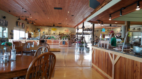 Interior of a rustic café with wooden decor, tables, and a display counter, featuring a warm, inviting atmosphere.