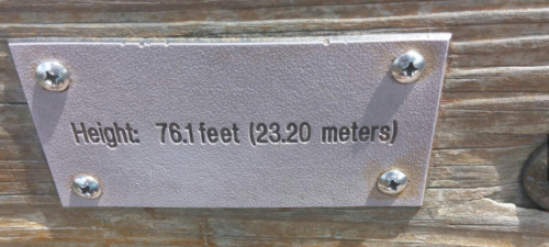 Sign displaying the height: 76.1 feet (23.20 meters) attached to a wooden surface.