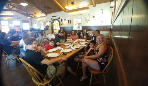 A group of people sitting around a large table in a restaurant, enjoying a meal together.