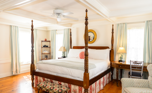 Bright bedroom featuring a four-poster bed, wooden furniture, and soft lighting, with a cozy, inviting atmosphere.
