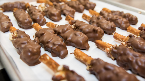 Chocolate-covered pretzel sticks arranged on a baking sheet lined with parchment paper.