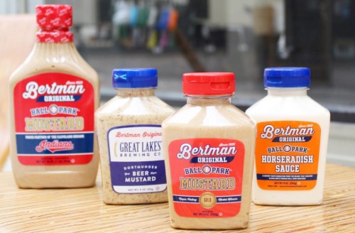Four bottles of Bertman Original condiments: Ball Park Mustard, Beer Mustard, and Horseradish Sauce on a countertop.