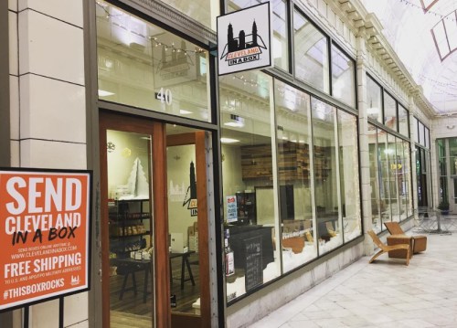 A storefront in a mall featuring "Cleveland in a Box" signage and a promotional poster for free shipping.