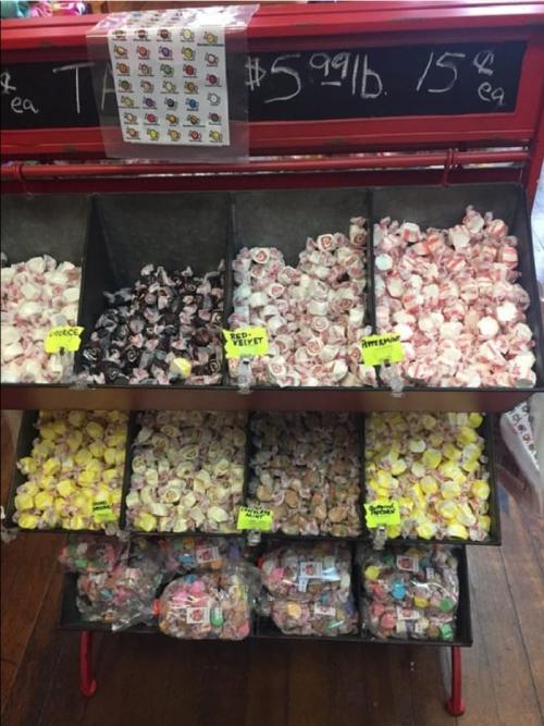 A display of colorful candies in bins, labeled with prices, showcasing various types and flavors.