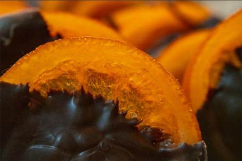 Close-up of orange slices coated in dark chocolate, showcasing their vibrant color and glossy texture.