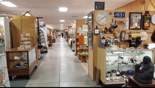 A wide aisle in an antique store, lined with display cases and various vintage items on shelves.