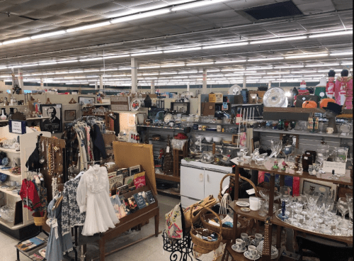 A spacious thrift store filled with various vintage items, clothing, and household goods on display.