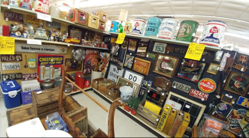A vintage shop display filled with various retro signs, memorabilia, and collectibles on shelves and walls.