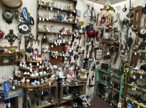 A cluttered antique shop filled with various vintage items, including figurines, lamps, and decorative objects.