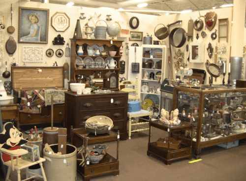 A vintage shop filled with various antiques, including furniture, glassware, and decorative items on display.