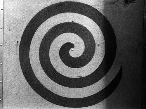 A black spiral design on a textured gray background.