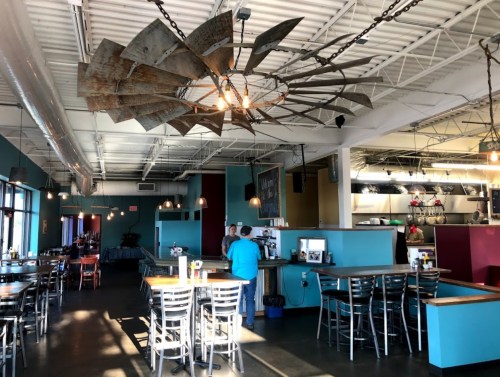Interior of a restaurant featuring colorful walls, a unique windmill chandelier, and a spacious dining area.