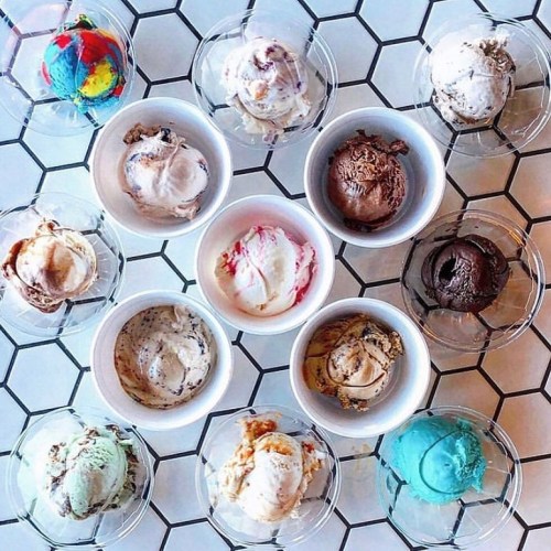 A variety of ice cream scoops in small bowls arranged on a geometric tiled surface.