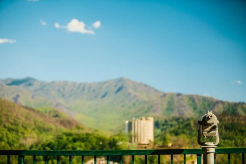 A scenic view of mountains and a building, with a telescope in the foreground against a clear blue sky.