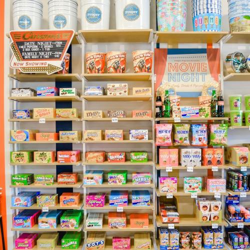 A colorful display of snacks and candies on shelves, promoting a movie night theme with various brands and treats.