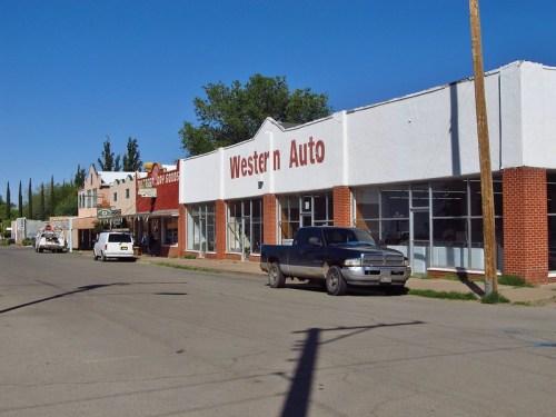 A street view featuring a Western Auto store and nearby buildings under a clear blue sky.