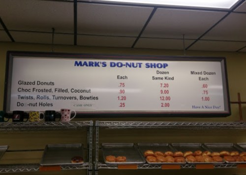 Menu board at Mark's Do-Nut Shop displaying prices for various donuts and pastries.