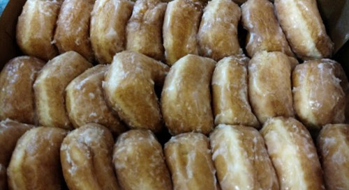 A close-up of a box filled with glazed donuts arranged in neat rows.