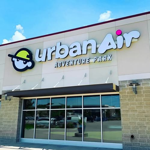 Sign for Urban Air Adventure Park, featuring a playful logo and bright blue sky in the background.