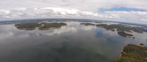 Aerial view of a serene lake with multiple islands and a cloudy sky reflecting on the water's surface.