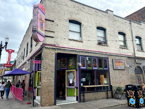 Voodoo Doughnut shop exterior with colorful signage and a brick facade, bustling street scene in Portland, Oregon.