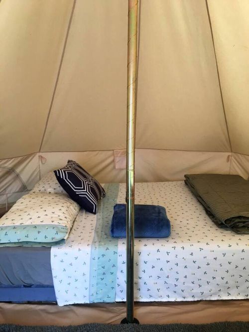 Cozy interior of a tent with neatly arranged bedding, pillows, and a blue blanket.