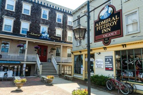 A quaint street scene featuring the Admiral Fitzroy Inn with a "Vacancy" sign and nearby shops and outdoor seating.