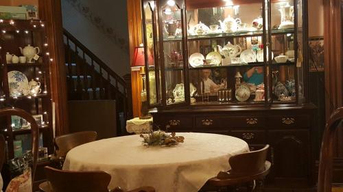 A cozy dining room with a round table, wooden chairs, and a glass display cabinet filled with fine china and collectibles.