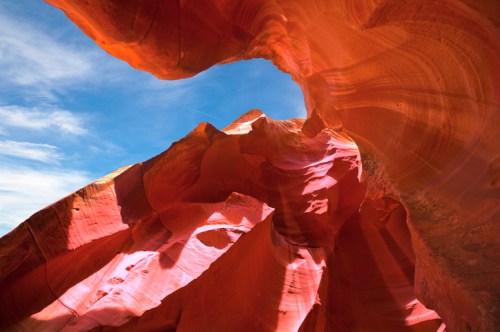 A stunning view of red rock formations and blue sky inside a canyon, showcasing natural curves and textures.