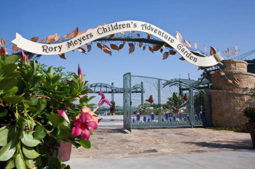 Entrance to Rory Meyers Children's Adventure Garden, featuring decorative arch and vibrant flowers in the foreground.