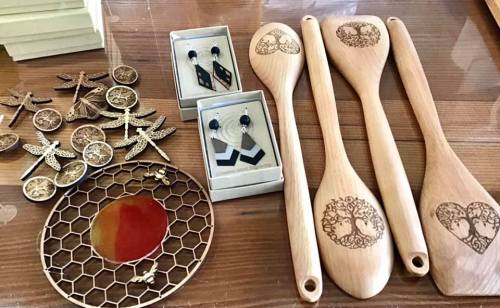 A display of handcrafted wooden spoons, earrings, and decorative items on a wooden table.