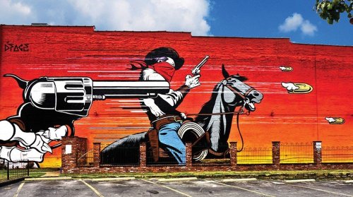 A vibrant mural depicting a masked cowboy on horseback, firing a revolver against a colorful sunset backdrop.
