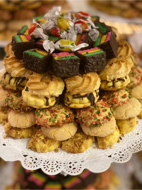 A colorful assortment of cookies and treats stacked on a decorative platter, topped with candies.