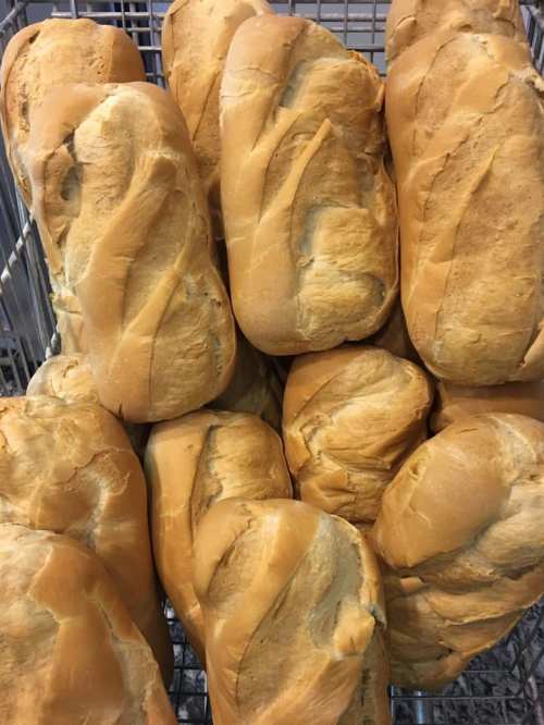 A close-up of freshly baked bread rolls stacked in a wire basket.