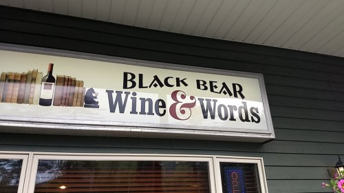 Sign for "Black Bear Wine & Words" featuring books and a wine bottle illustration.