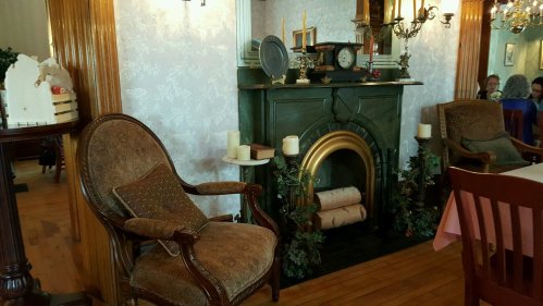 Cozy interior featuring a vintage armchair, a decorative fireplace, and elegant wall decor.