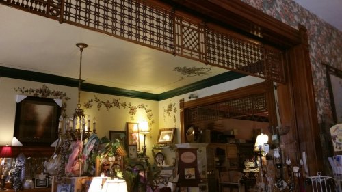 A cozy vintage shop interior with ornate woodwork, floral wallpaper, and various decorative items displayed.