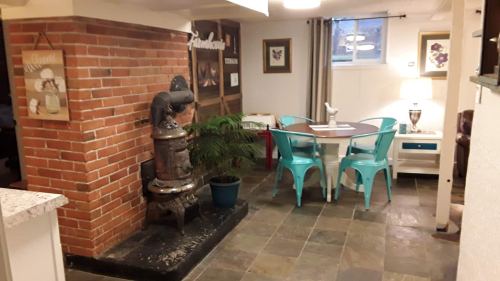 Cozy basement dining area with a brick wall, vintage stove, teal chairs, and a small table surrounded by decor.