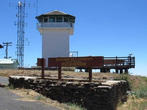 Boucher Hill Lookout tower with a sign, surrounded by dry grass and clear blue sky in Palomar Mountain State Park.